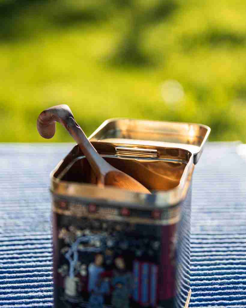 Properly storing your coffee beans by putting them in an airtight container with a spoon. 