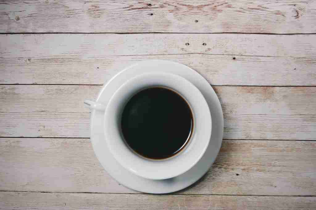 Black coffee in a white porcelain cup on a wooden table