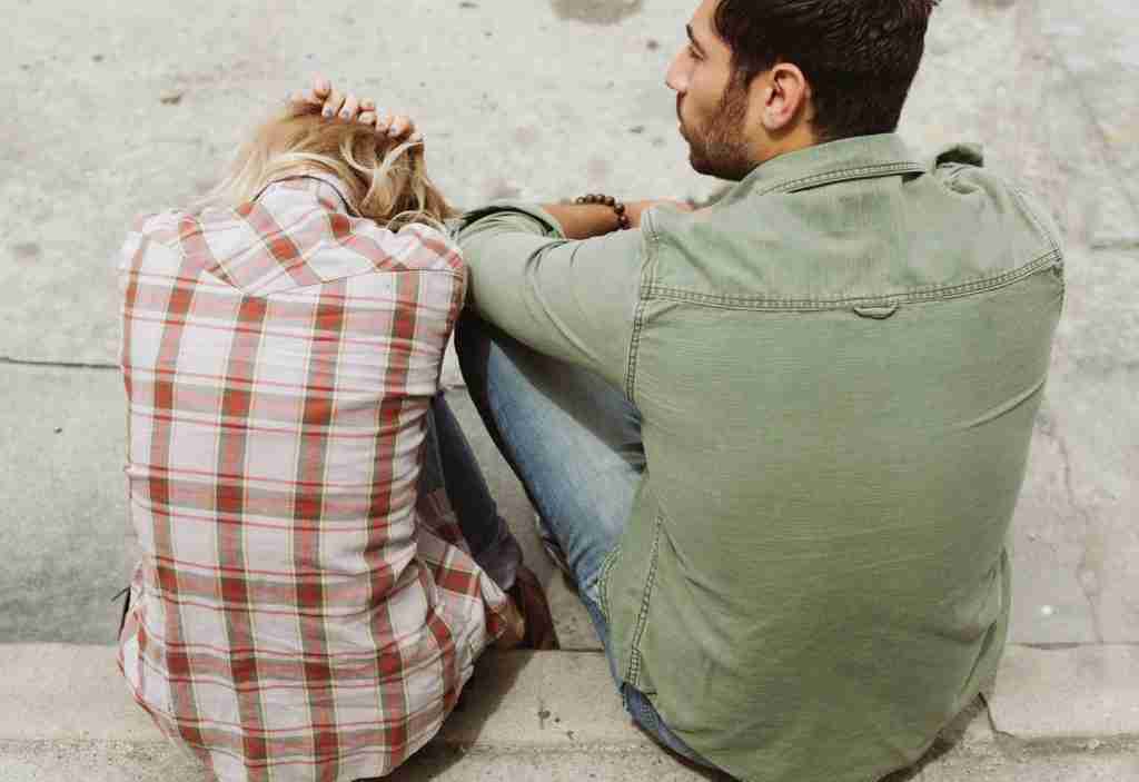 Man in green button down and woman. in plaid sitting next to each other. 