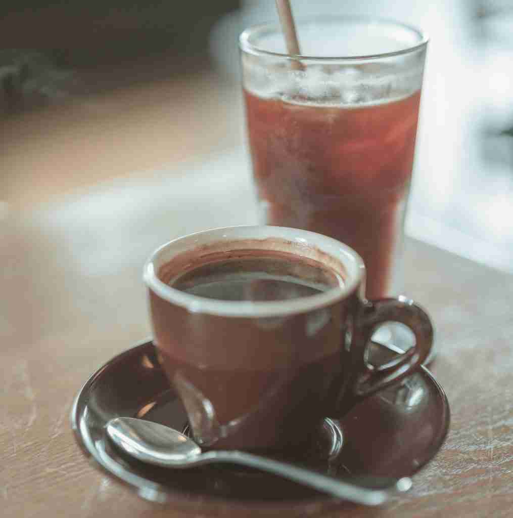 a cup of hot coffee next to a glass of iced coffee