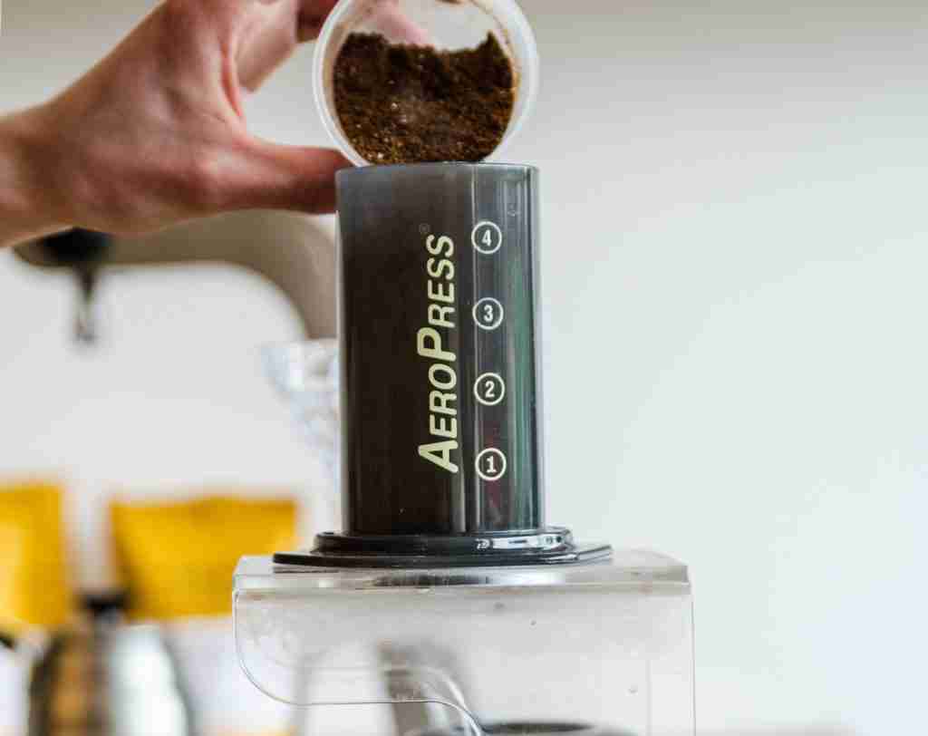 pouring ground coffee into aeropress