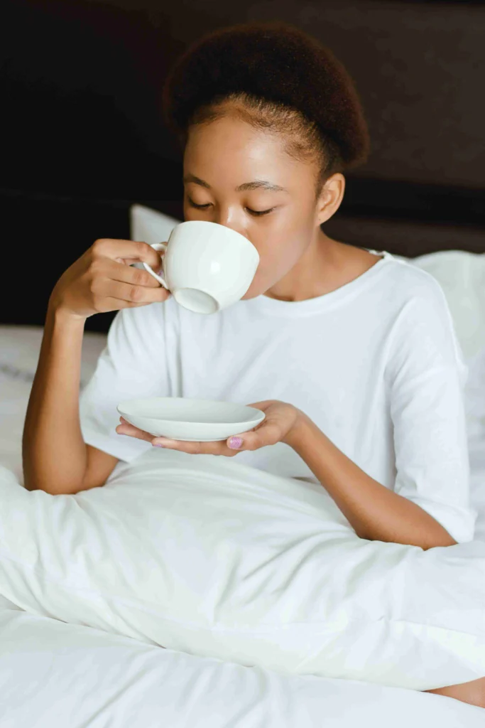 Coffee After Dinner: Is It Bad for You? 9 Woman sipping coffee from a cup and saucer in bed