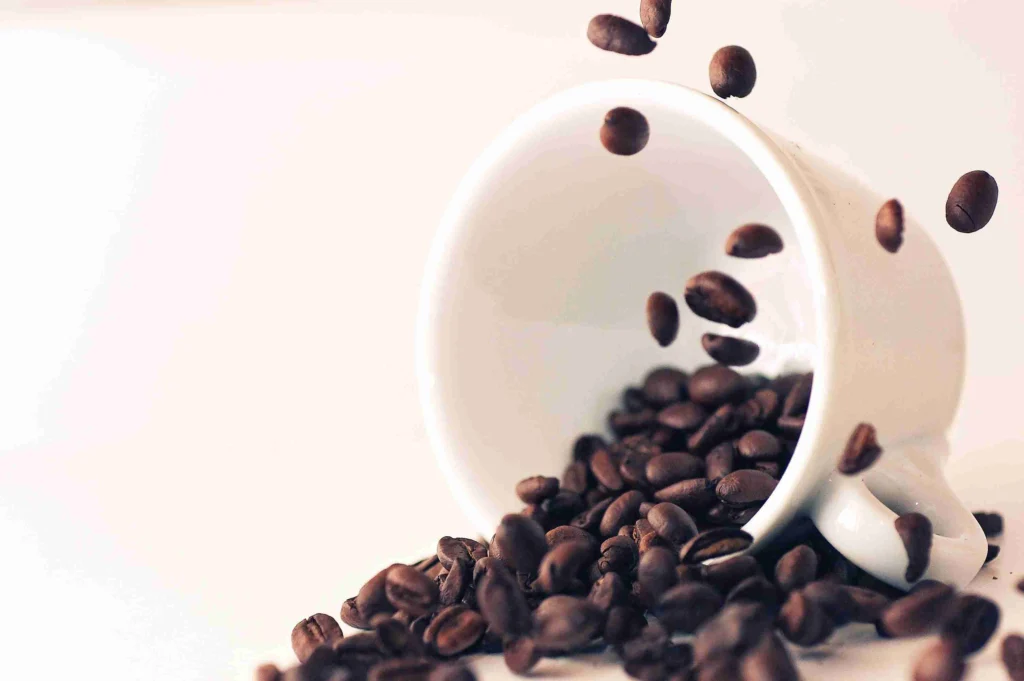 How long does 2 cups of coffee stay in your system 8 Coffee beans spilling out of a tipped-over white cup